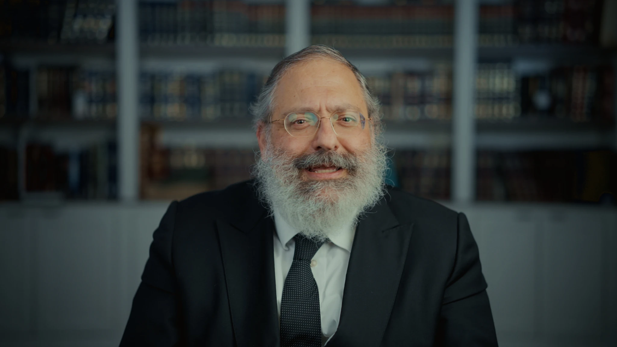 A seated interview with bookshelves in the background