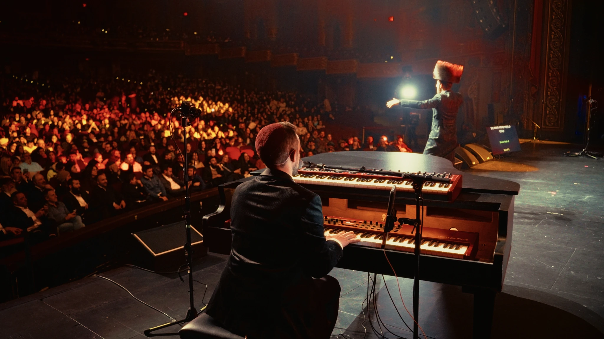 A pianist and singer performing for a theater audience